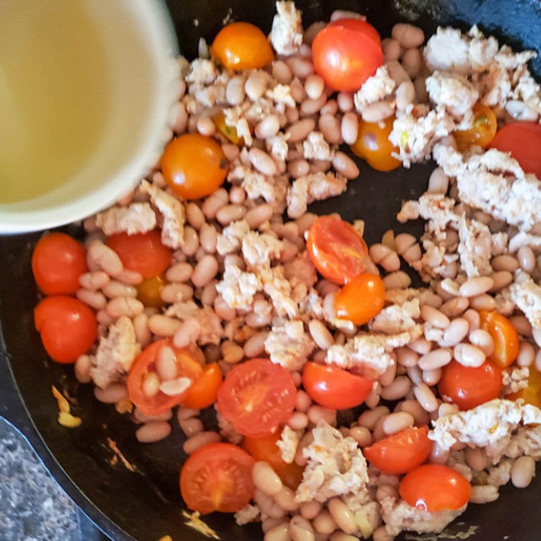 process step 2 tomatoes and chicken cooking in a cast iron skillet