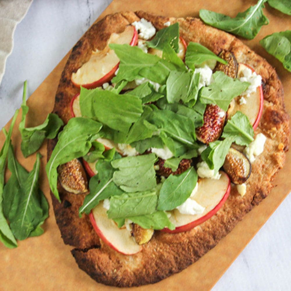 apple fig flatbread out of the oven and sprinkled with baby arugula