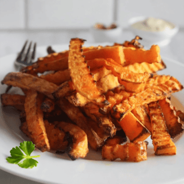 butternut squash fries on a plate with dipping sauce in the back