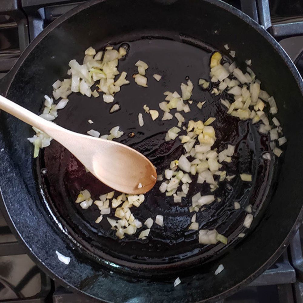 process step for spinach balls, minced onions cooking in a skillet