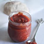 Pizza Sauce in a jar with a spoon next to it.