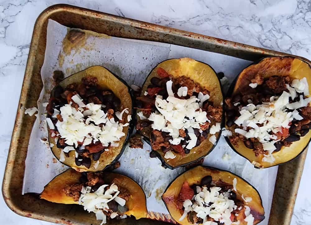 stuffed acorn squash on a tray ready for the oven
