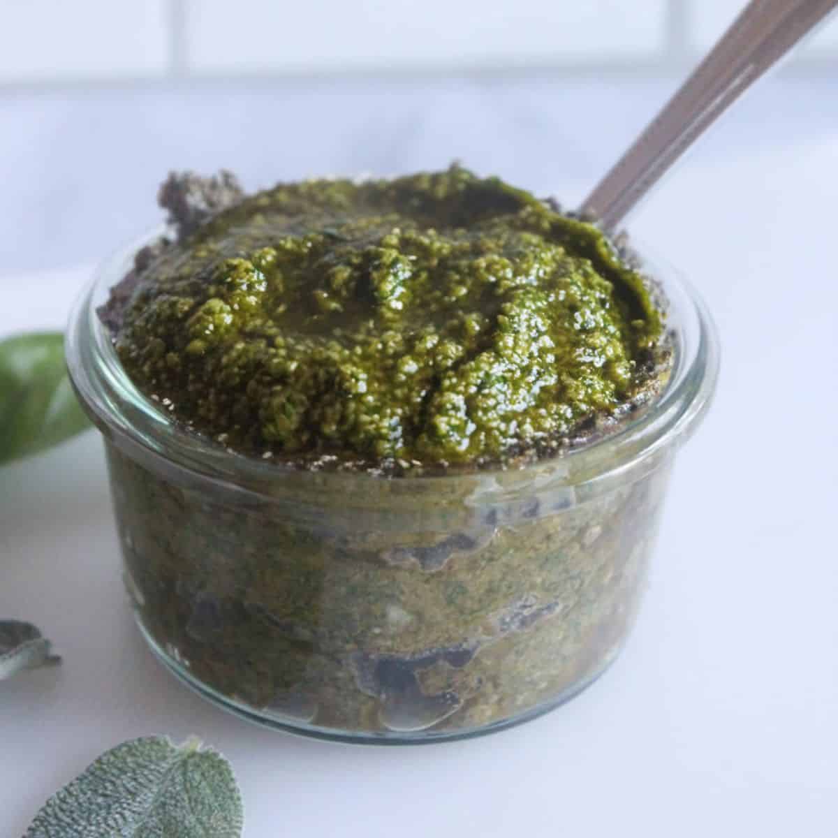 a picutre of pesto sauce in a jar with a spoon