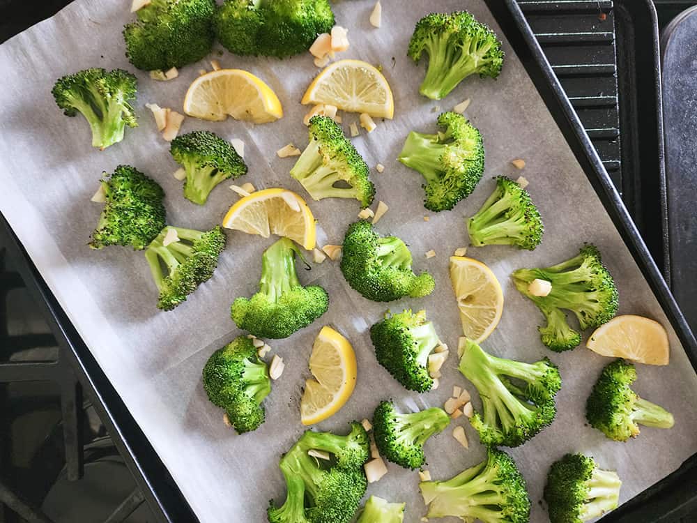 step 2 broccoli on a sheet pan with lemon slices and garlic