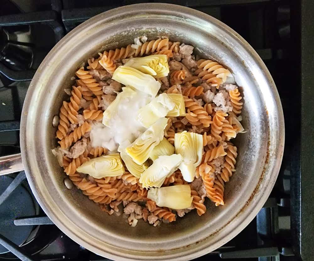 overhead view of cooked pasta and turkey with artichokes