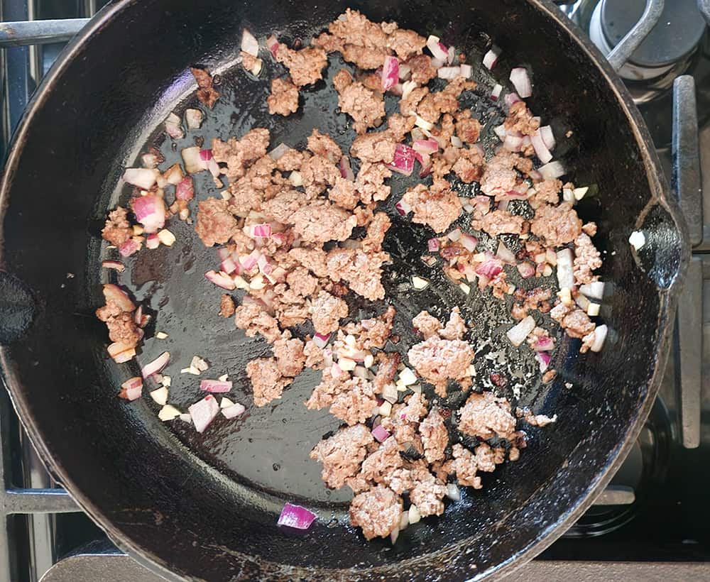 a picture of the meat and onions cooking in a skillet