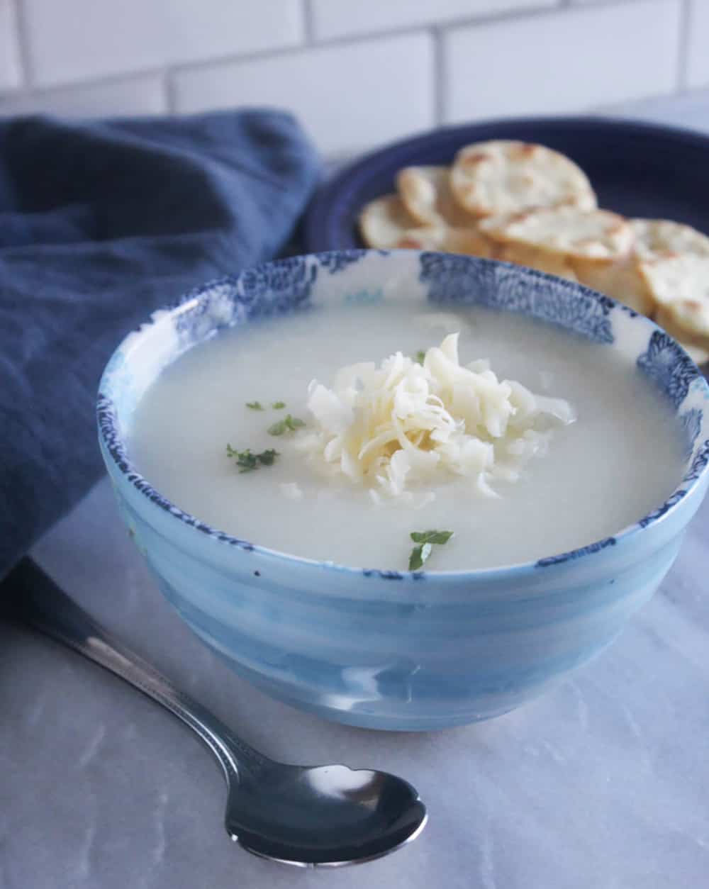 a close up of cauliflower soup in a bowl with cheese on top