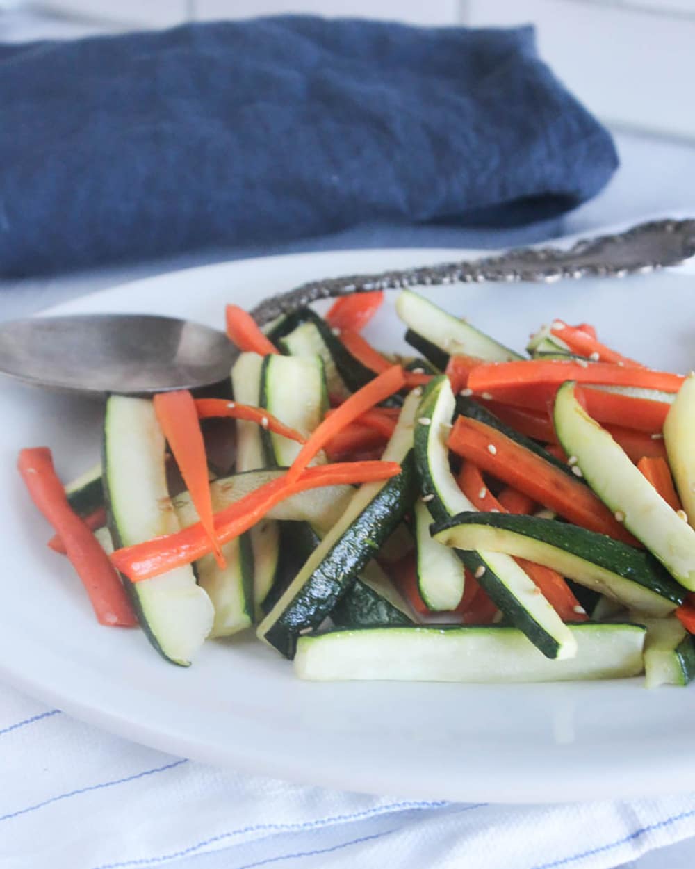 A picture of zucchini and carrots on a plate with a spoon