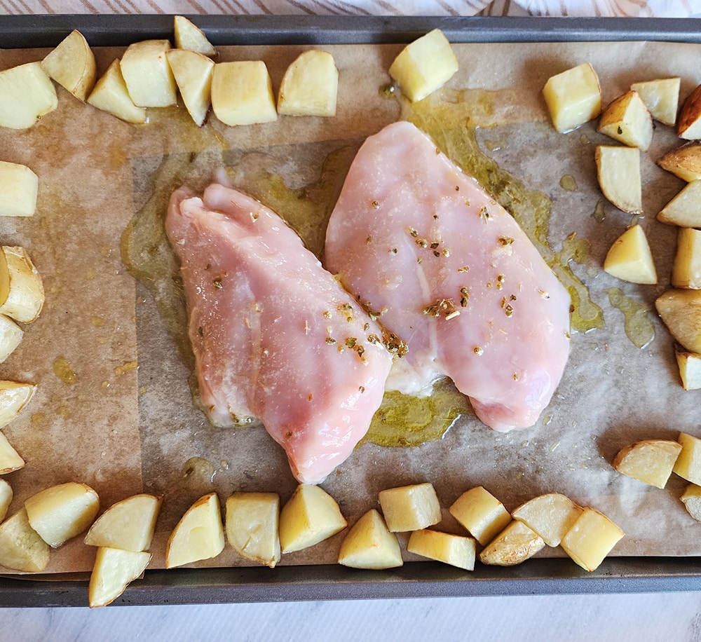 A picture of potato chunks around the perimeter with chicken breasts in teh center of a pan