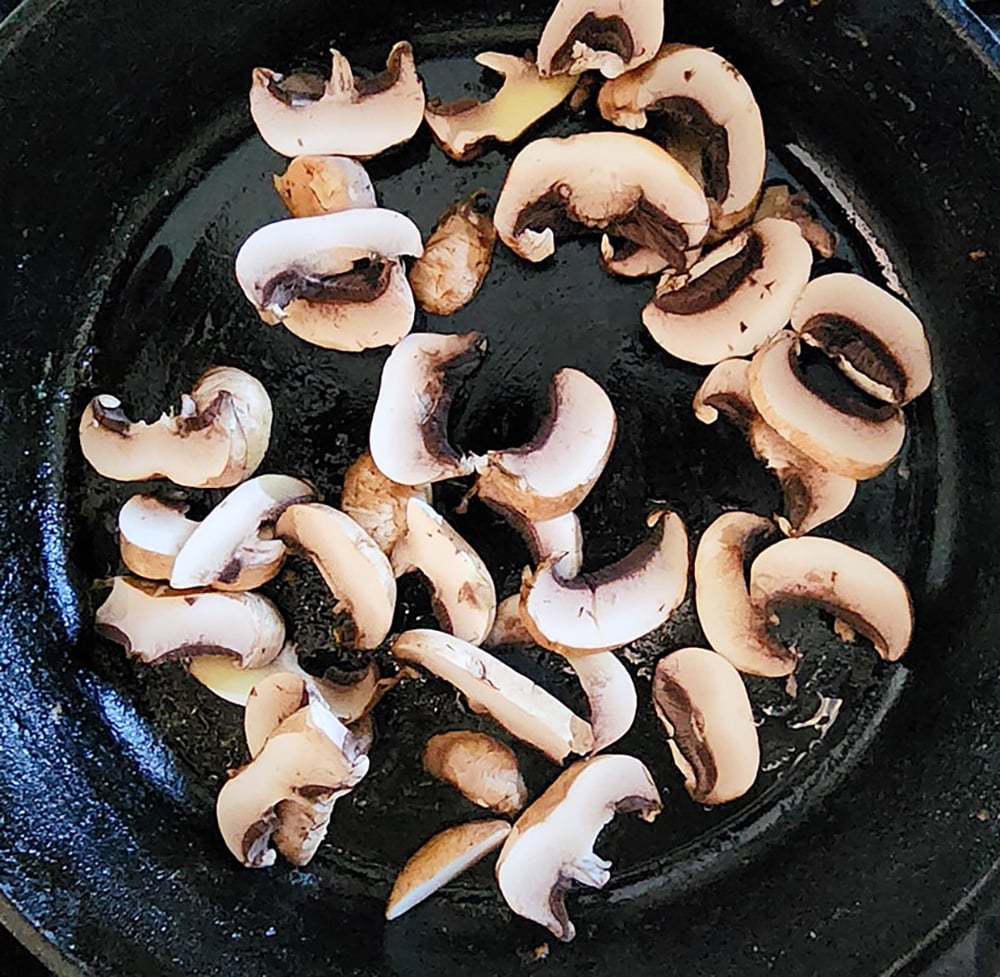 Step 3 cook the mushrooms, a photo of the mushrooms in a cast iron skillet