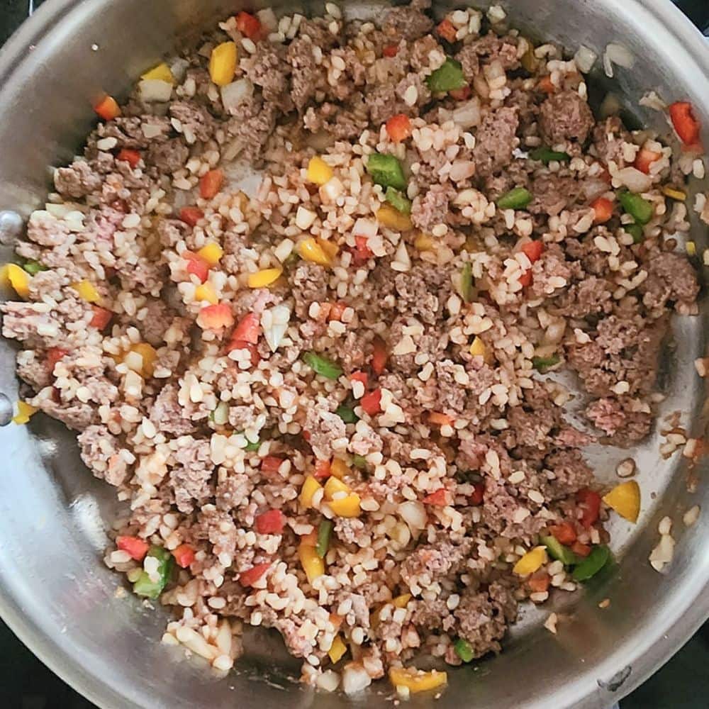 cooked ground beef in a skllet with peppers, onions and rice