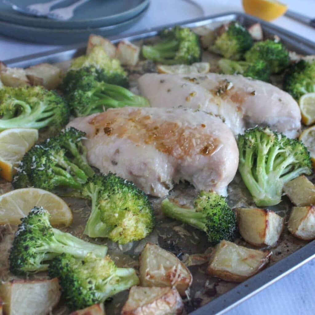 A picture of cooked chicken breasts, broccoli and potatoes on a sheetpan