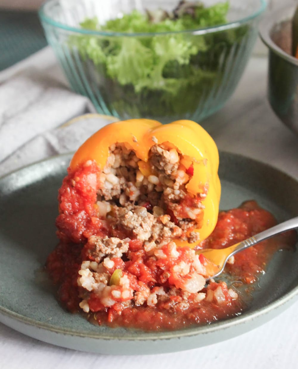 A picture of stuffed bell pepper with stuffing coming out of it with a fork