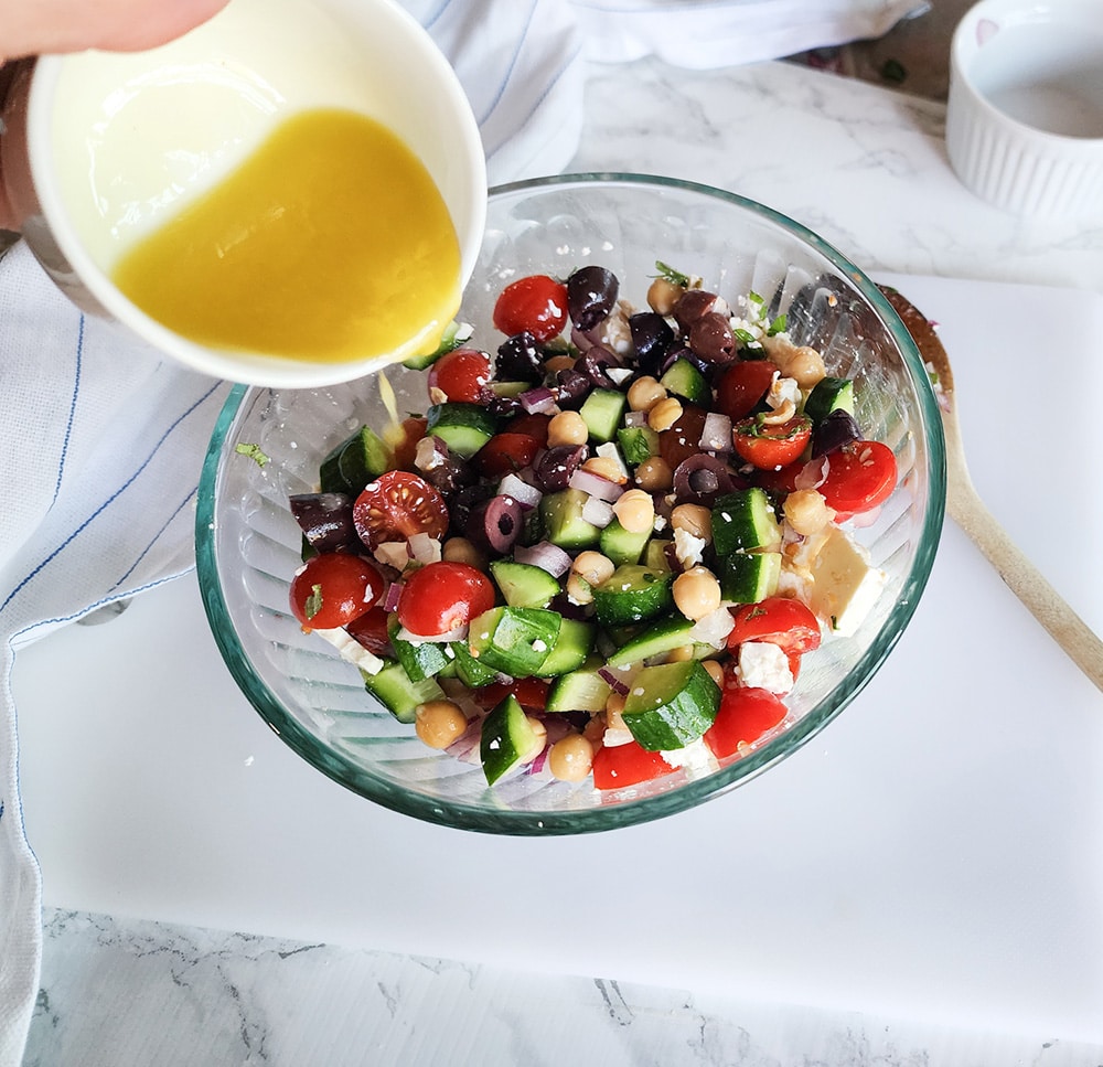 A picture of dressing pouring into the salad in a large bowl