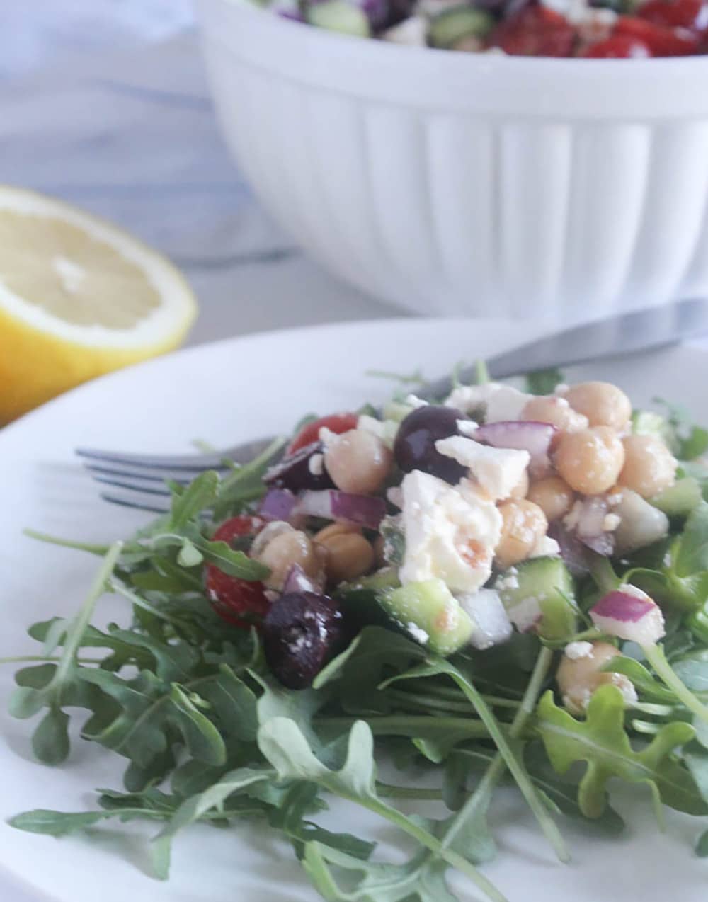 A picture of cucumber salad on a white plate over arugula 