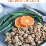 a picture of orange chicken on a plate with green beans and orange slices