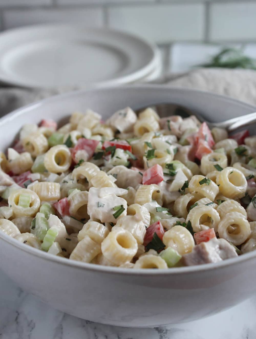 A bowl of chicken macaroni salad in a bowl with a spoon