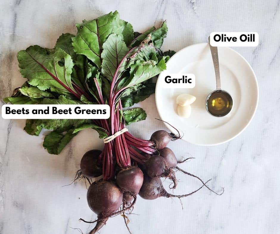 A picture of the ingredients needed to make sauteed beets: beets with greens, garlic, olive oil