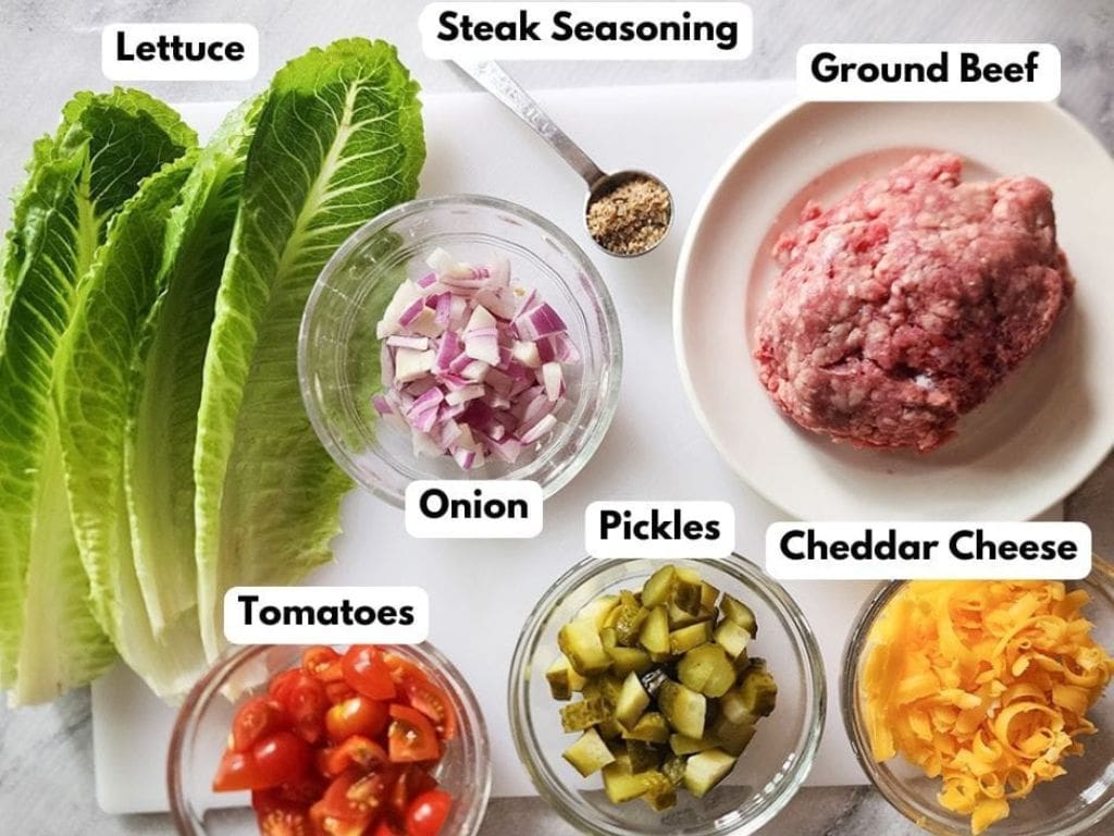 a labeled photograph of the ingredients needed to make cheeseburger lettuce wraps Lettuce, onion, steak seasoning, pickles, comateos and cheddar cheesse