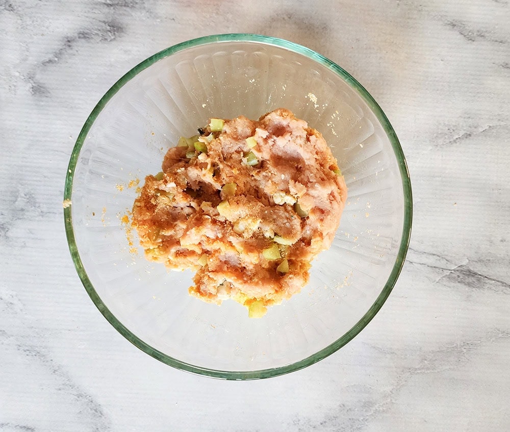 a picture of ground chicken in a glass bowl, mixed with chopped celery, blue cheese and hot sauce