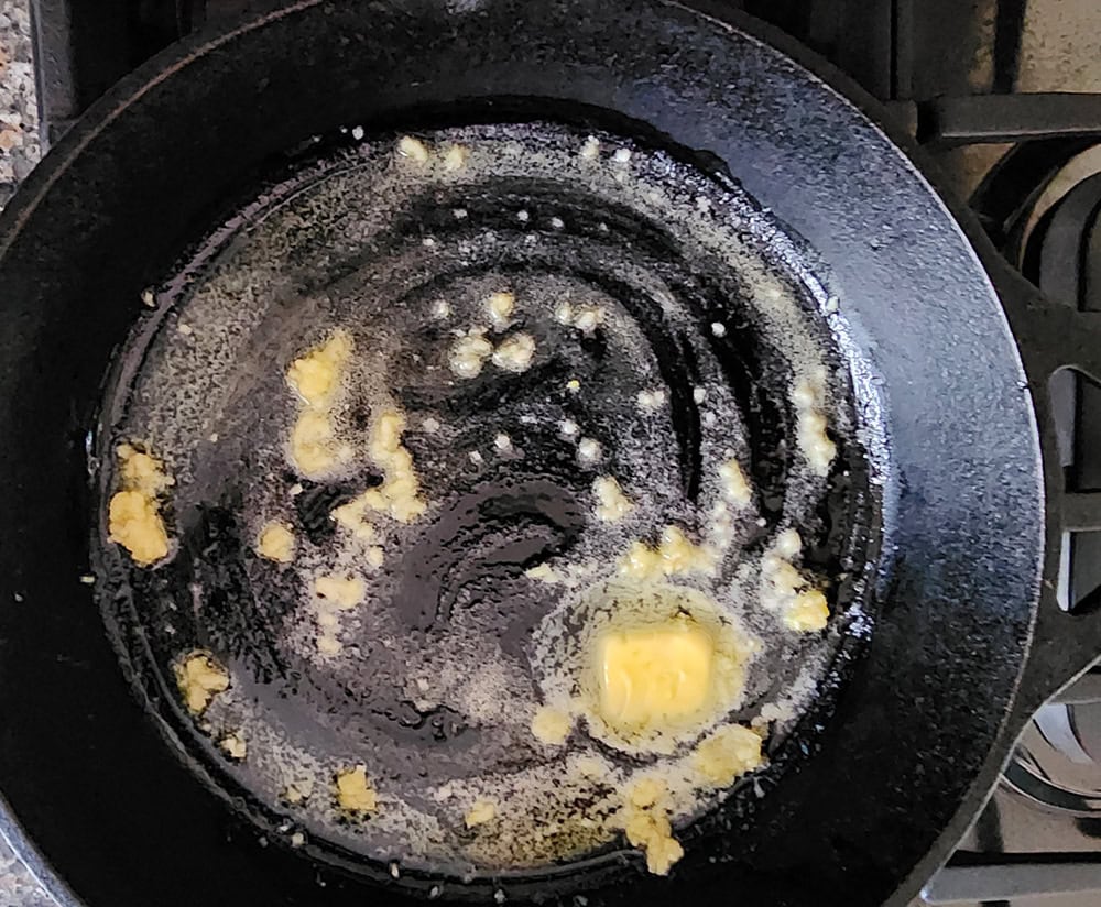 a picture of butter melting in a skilet with garlic