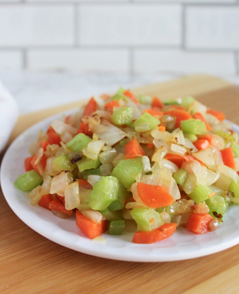 a picture of cooked mirepoix on a white plate sitting on top of a cutting board
