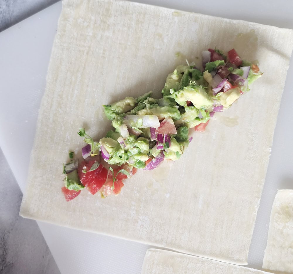 a picture of an egg roll wrapper with the filling in the center before rolling it up