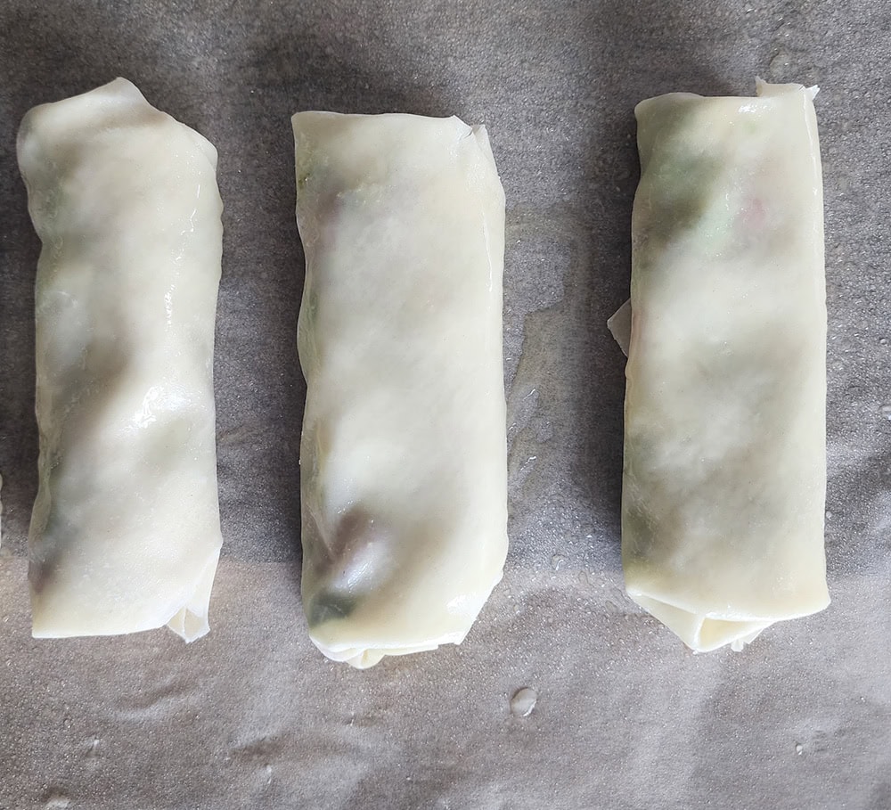 Step 5: egg rolls wrapped and placed on a baking tray ready for the oven.
