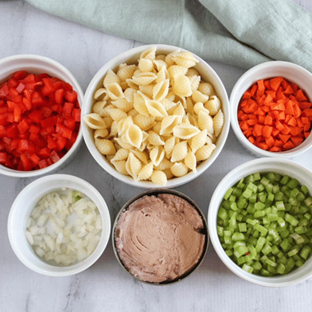 a picture of the ingeredients for tuna sala bell peppers, pasta, carrots, onions, tuna and celery