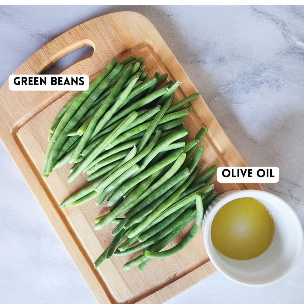 a picture of green beans on a cutting board and a small bowl of olive oil on the side