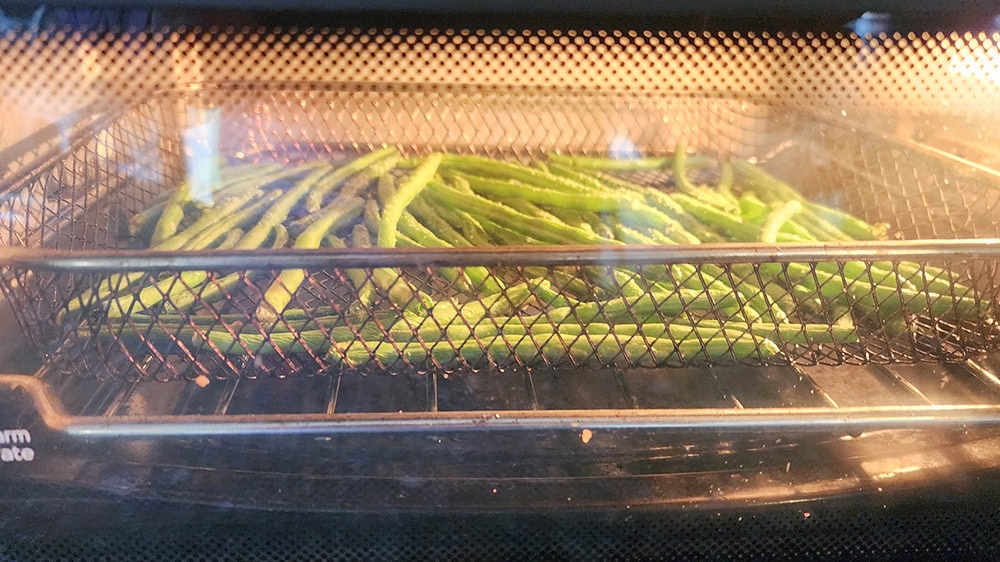 a picture of green beans in an air fyer oven cookiing