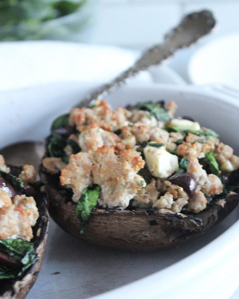 delicious stuffed portobello mushrooms in a white serving dish with a spoon