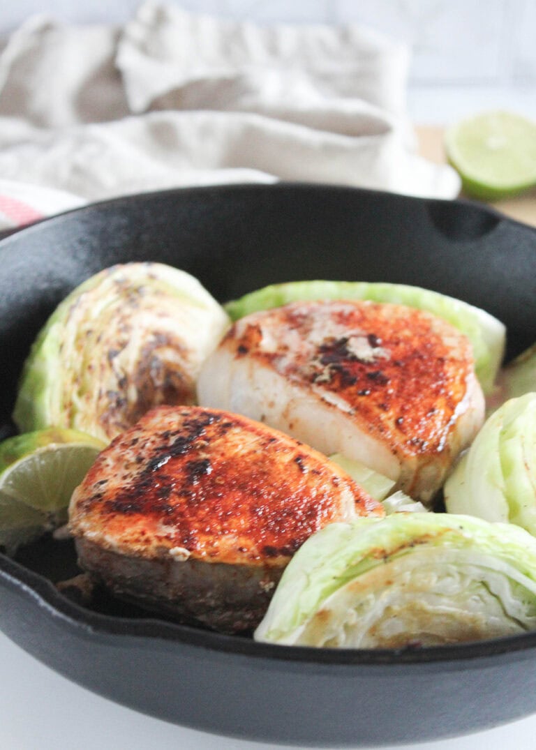 a picutre of golden brown boneless pork chops in a skillet with cabbage wedges