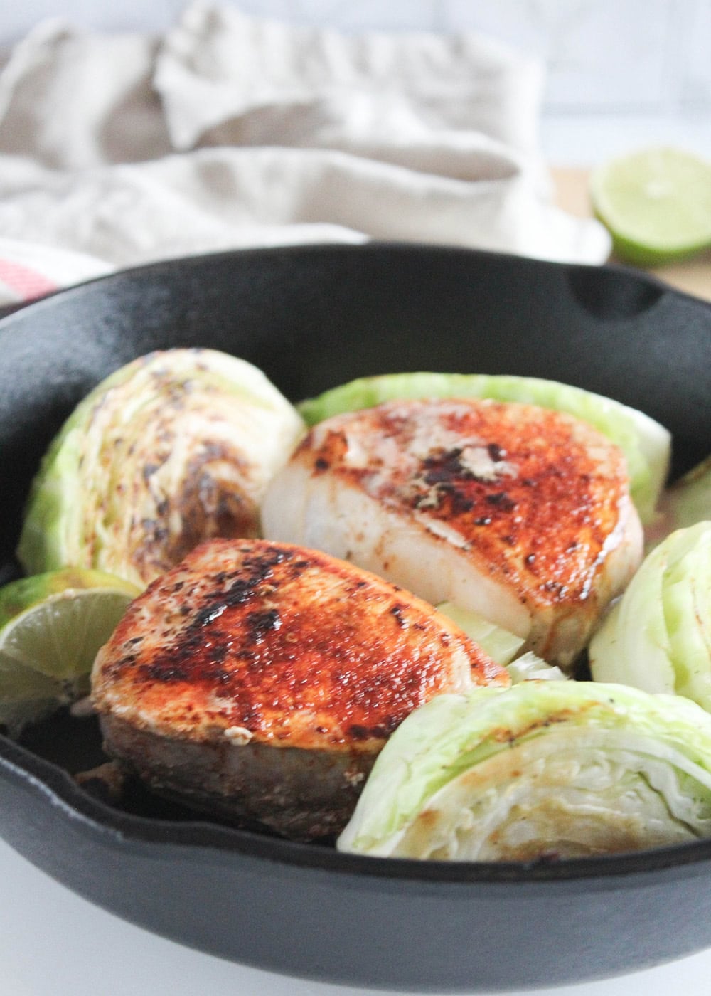 a picutre of golden brown boneless pork chops in a skillet with cabbage wedges