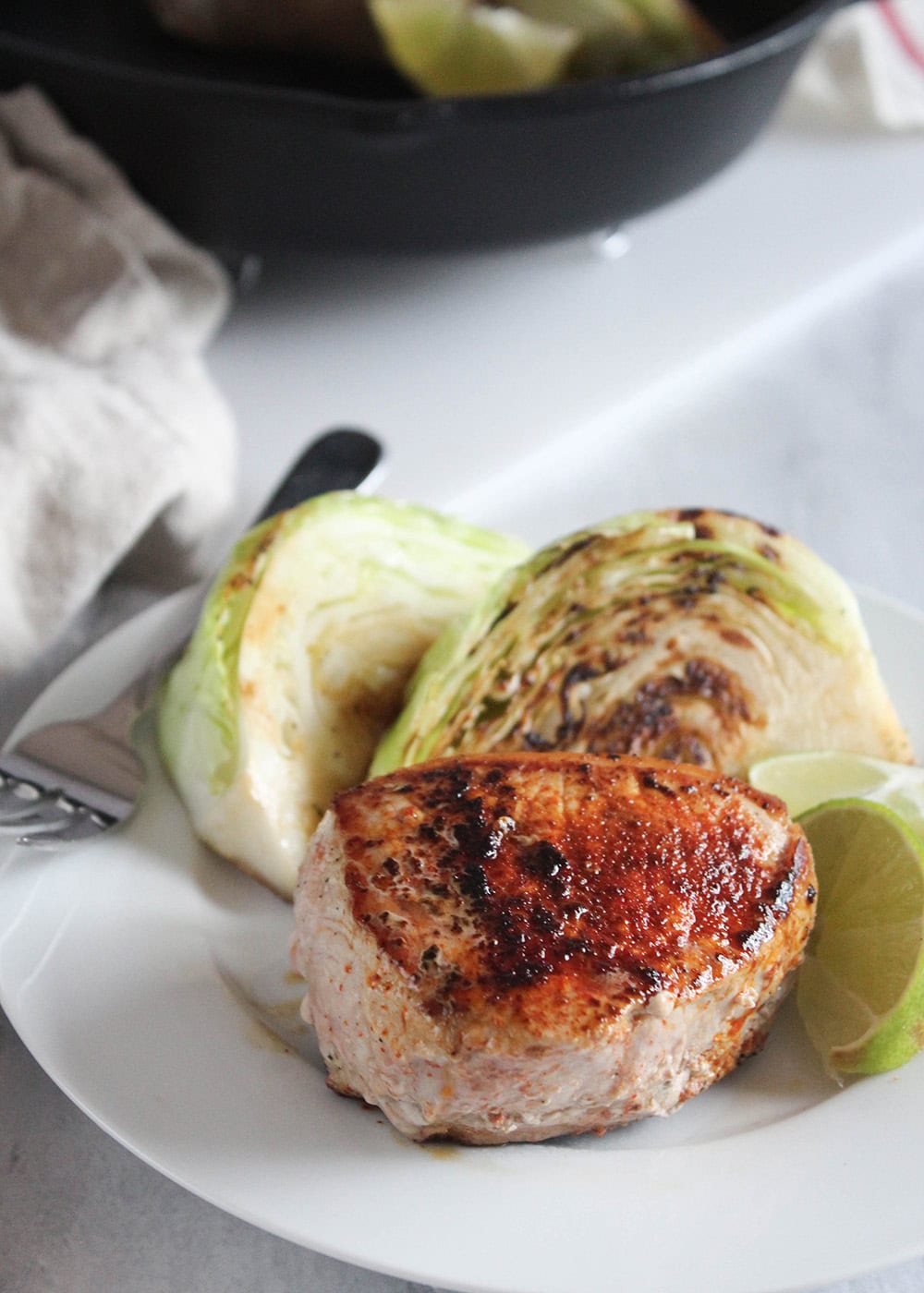a picutre of a golden brown boneless pork chop on a plate with cabbage wedges