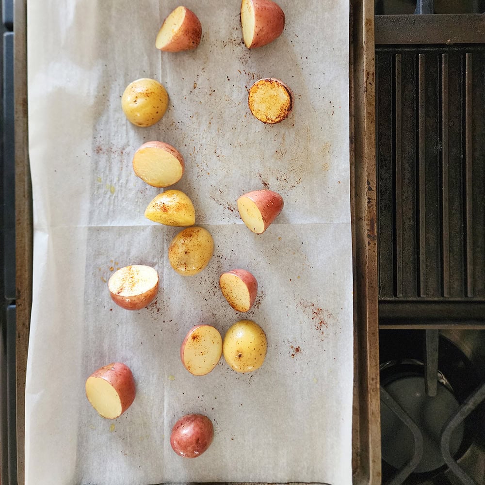 potato chunks on a sheet pan with chili powder sprinkled on them