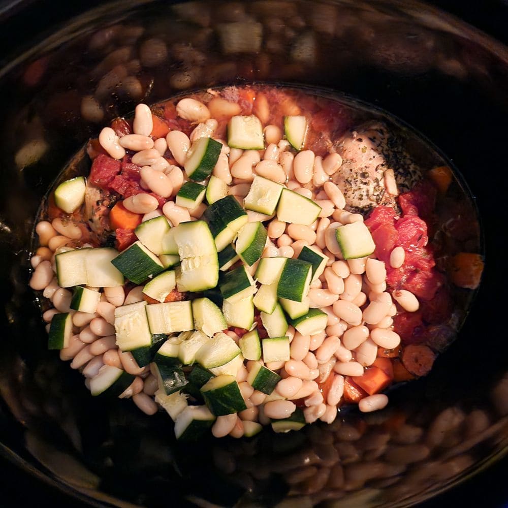 Process step 4, chopped zucchini and beans added to the slow cooker after several hours of cooking
