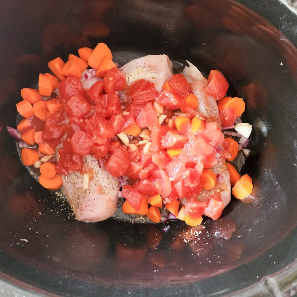 Process step 3 for tuscan chicken. tomatoes added to the ingredients in theslow cooker