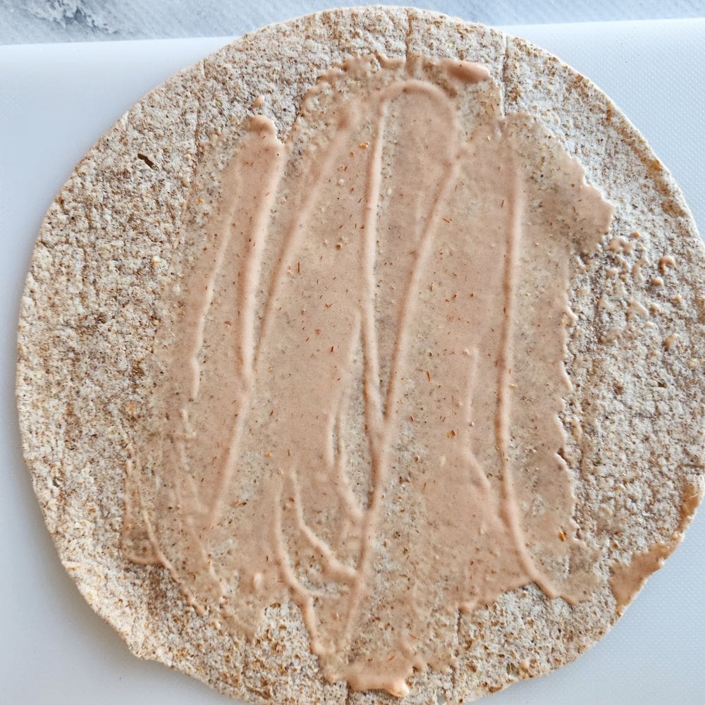a picture of process step 2, a tortilla with russian dressing spread on it
