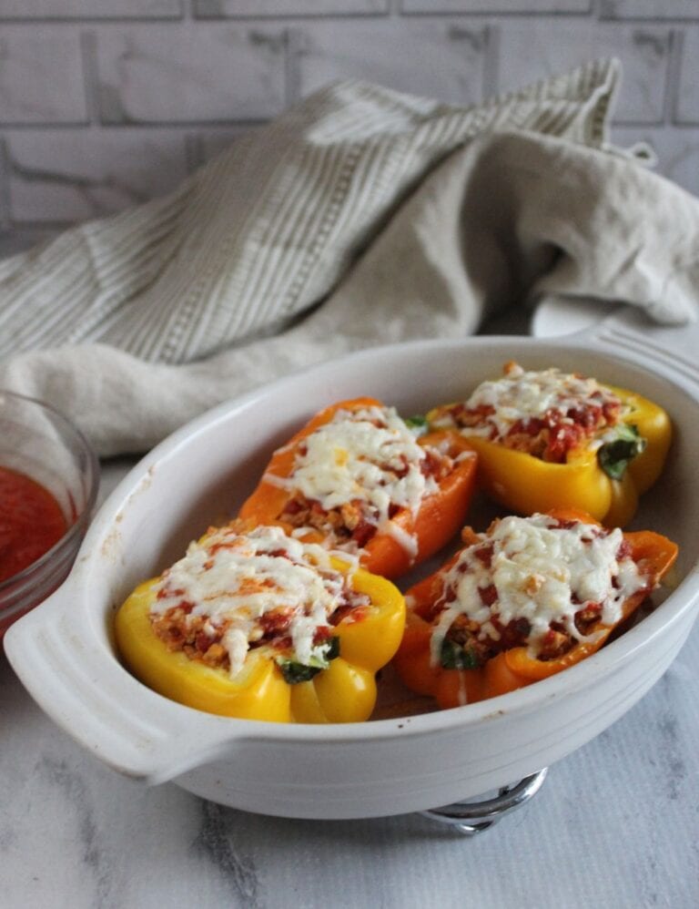 a picture of stuffed bell peppers parmesan style in a white casserole dish