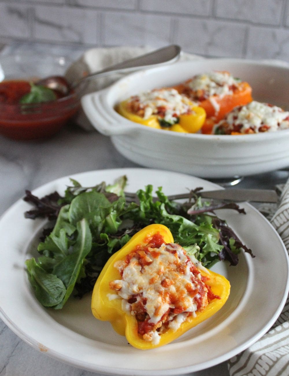 a chicken parm stuffed pepper on a plate with a salad
