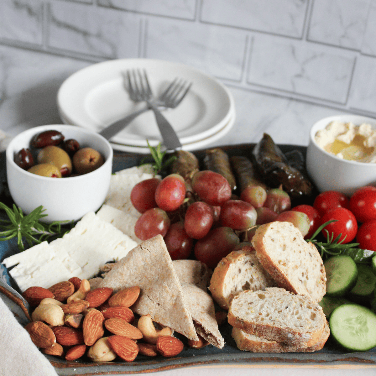 a picture of a mezze style board filled with fruit, nuts, olives hummus and veggies