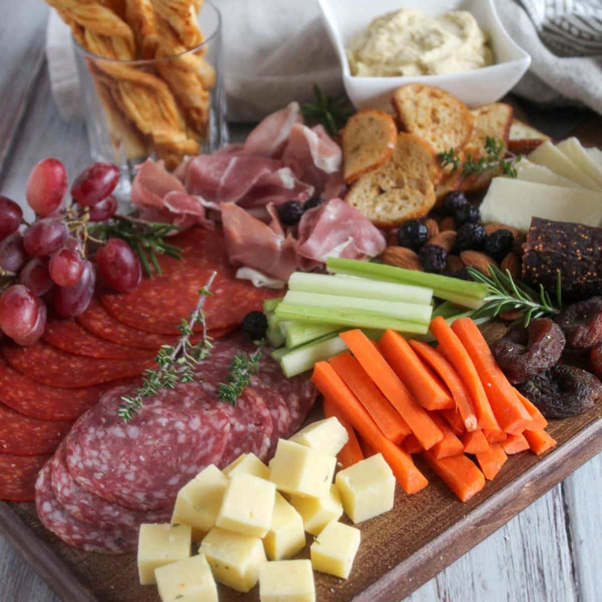 a picture of a charcuterie board with cured meats, veggies and crackers