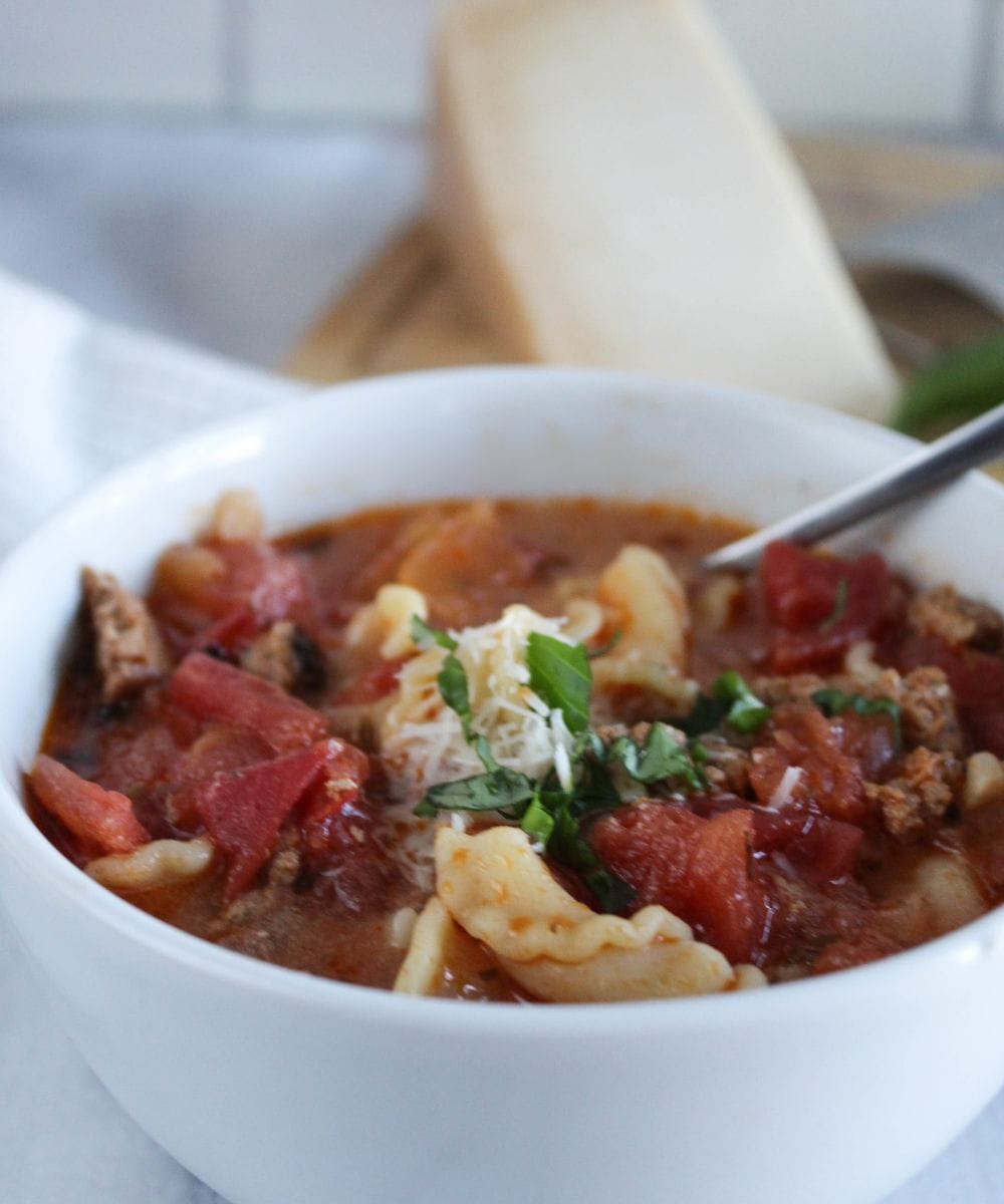 a close up photo of lasagna soup in a bowl with a spoon