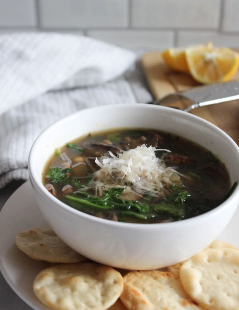 a close up picture of mushroom kale soup in a bow topped with parmesan cheese