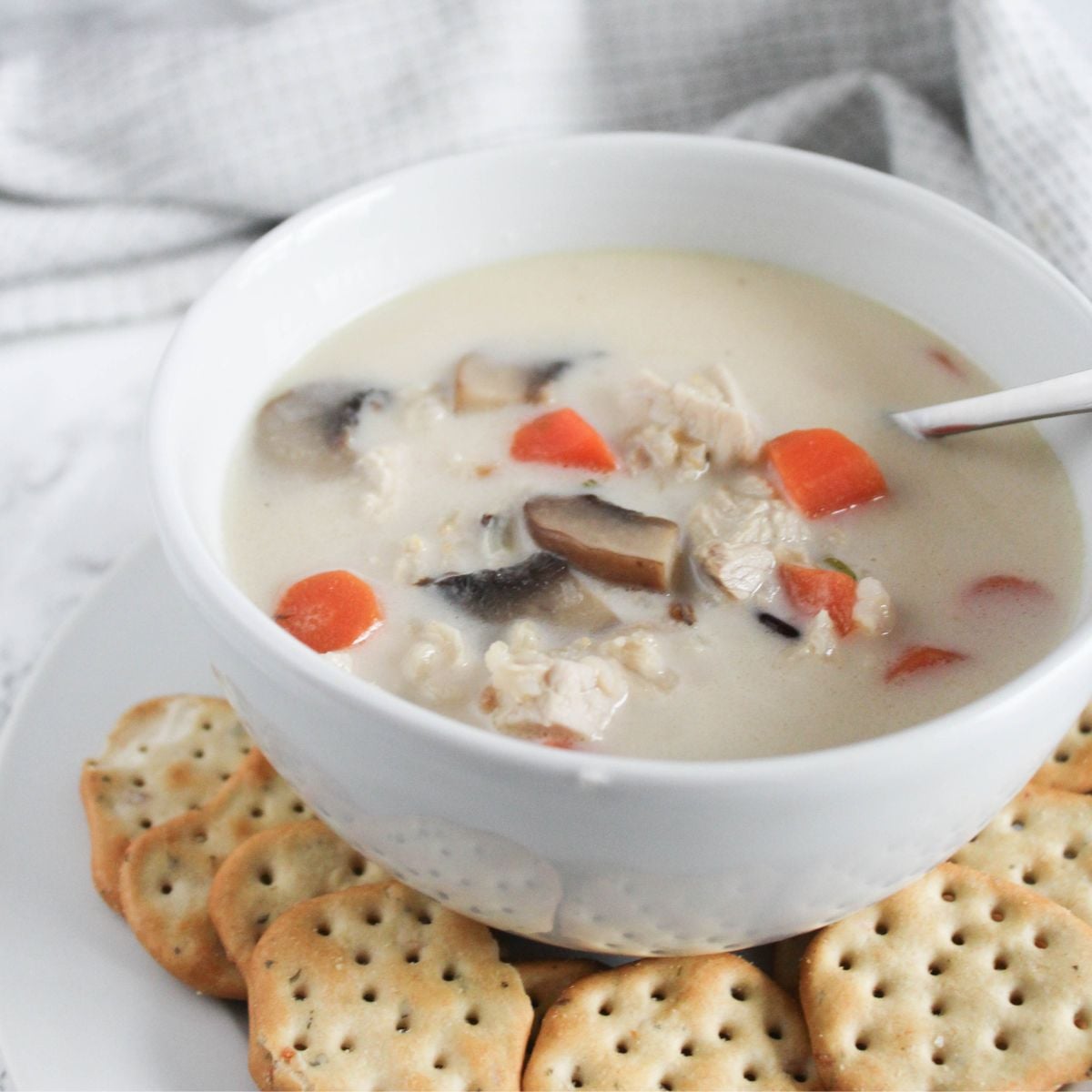 a close up picture of creamy turkey soup in a white bowl with a spoon