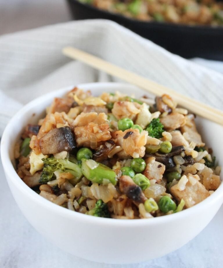 pork fried rice in a white bowl with chopsticks on the side of the bowl