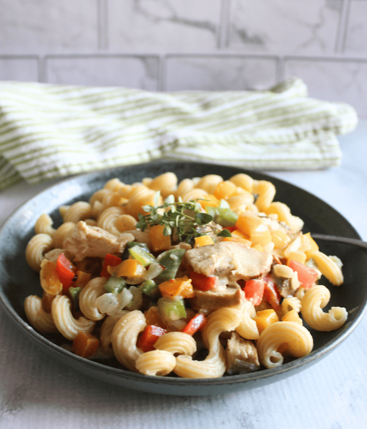 plated rasta pasta on a grey plate with a green and white cloth behind it