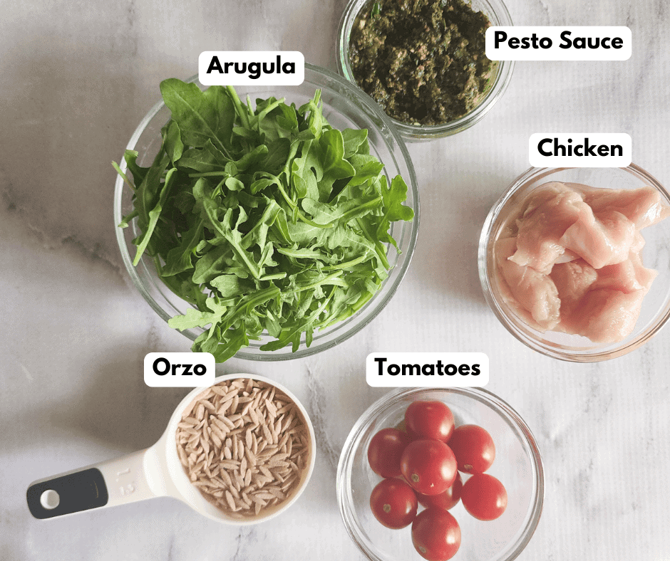 a picture of the ingredients needed to make pesto chicken: orzo, tomatoes, chicken, pesto sauce, arugula