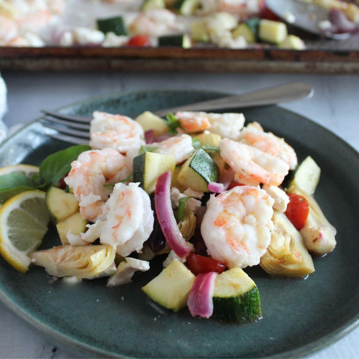 a picture of sheet pan shrimp and veggies on a blue plate with a fork